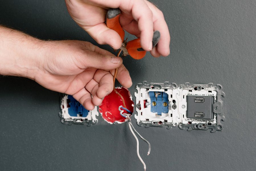 Hands wiring wall outlets during an installation