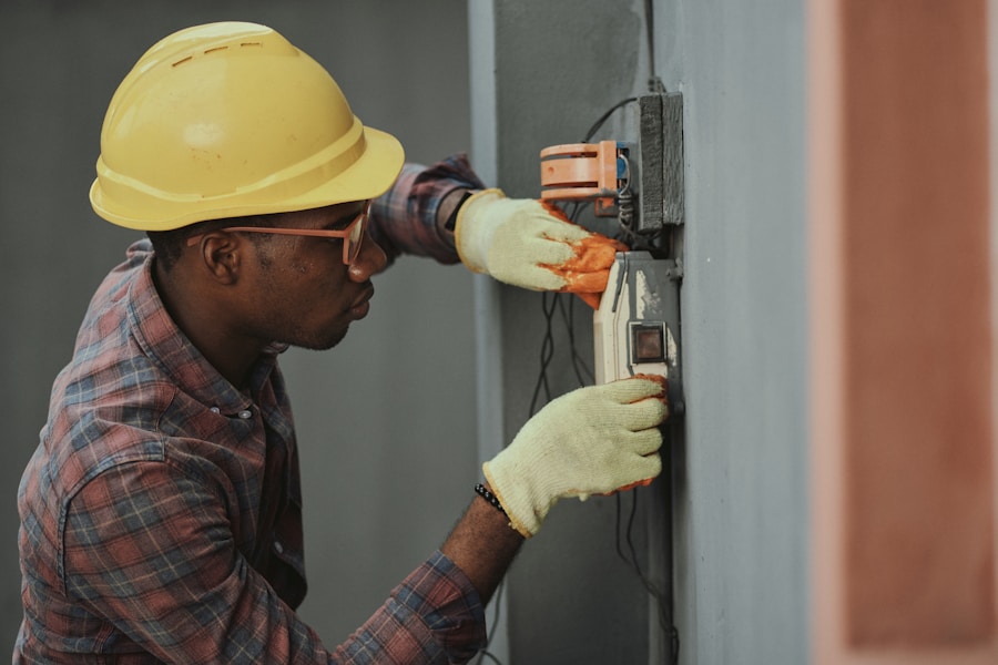 Electrician working on a wall-mounted electrical box at a job site